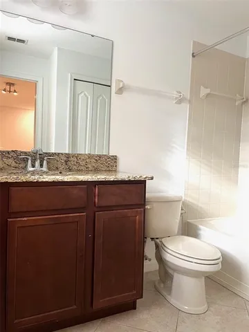 a bathroom with a granite countertop toilet sink and mirror