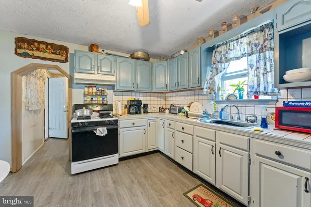 a kitchen with granite countertop a refrigerator a sink dishwasher and white cabinets with wooden floor