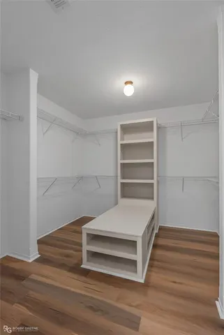 a room with a chandelier fan and wooden floor