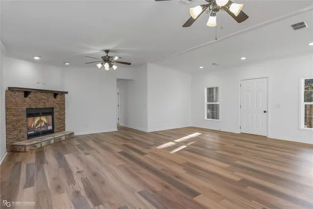 a view of an empty room with a window and a kitchen
