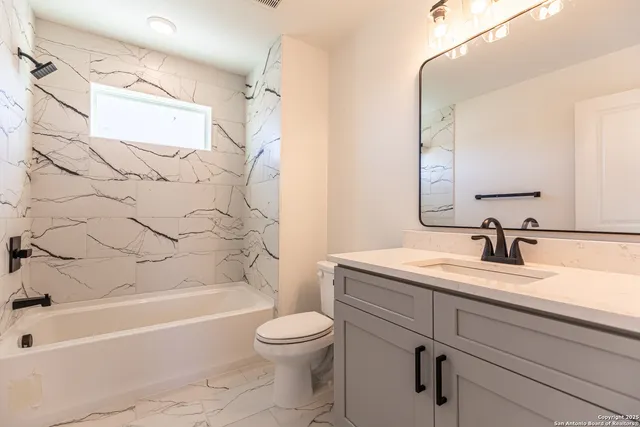 a bathroom with a granite countertop sink a toilet and bathtub