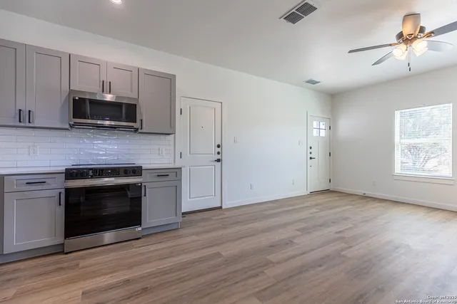 a kitchen with granite countertop a stove top oven a sink and dishwasher a microwave oven with wooden floor