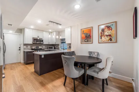 a kitchen with granite countertop a dining table chairs cabinets a sink and a counter top space