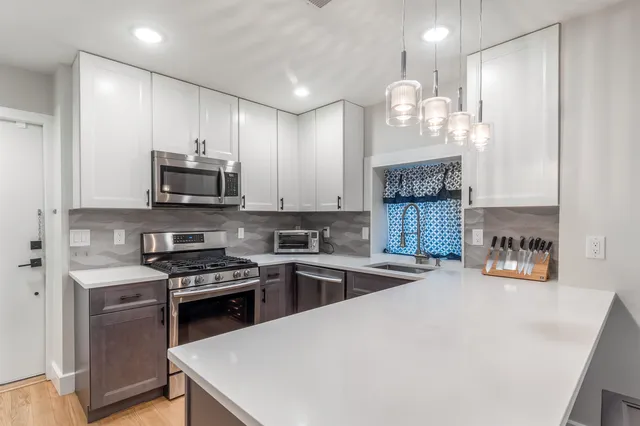 a kitchen with stainless steel appliances a stove a sink a microwave a refrigerator and cabinets