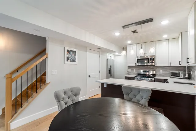 a large white kitchen with lots of counter space a sink a refrigerator and cabinets
