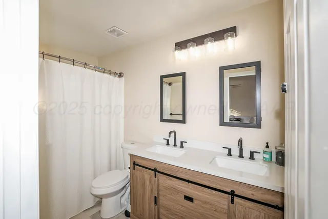 a bathroom with 2 sink toilet and a mirror