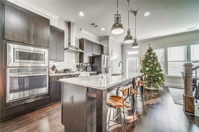 a kitchen with granite countertop a stove a sink dishwasher a refrigerator with wooden floor