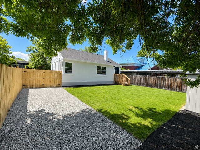 266 700 West Provo, UT 84601 - Photo 17 of 18 Fenced backyard featuring a gravel driveway, wood deck with stairs, white siding, and a manicured lawn