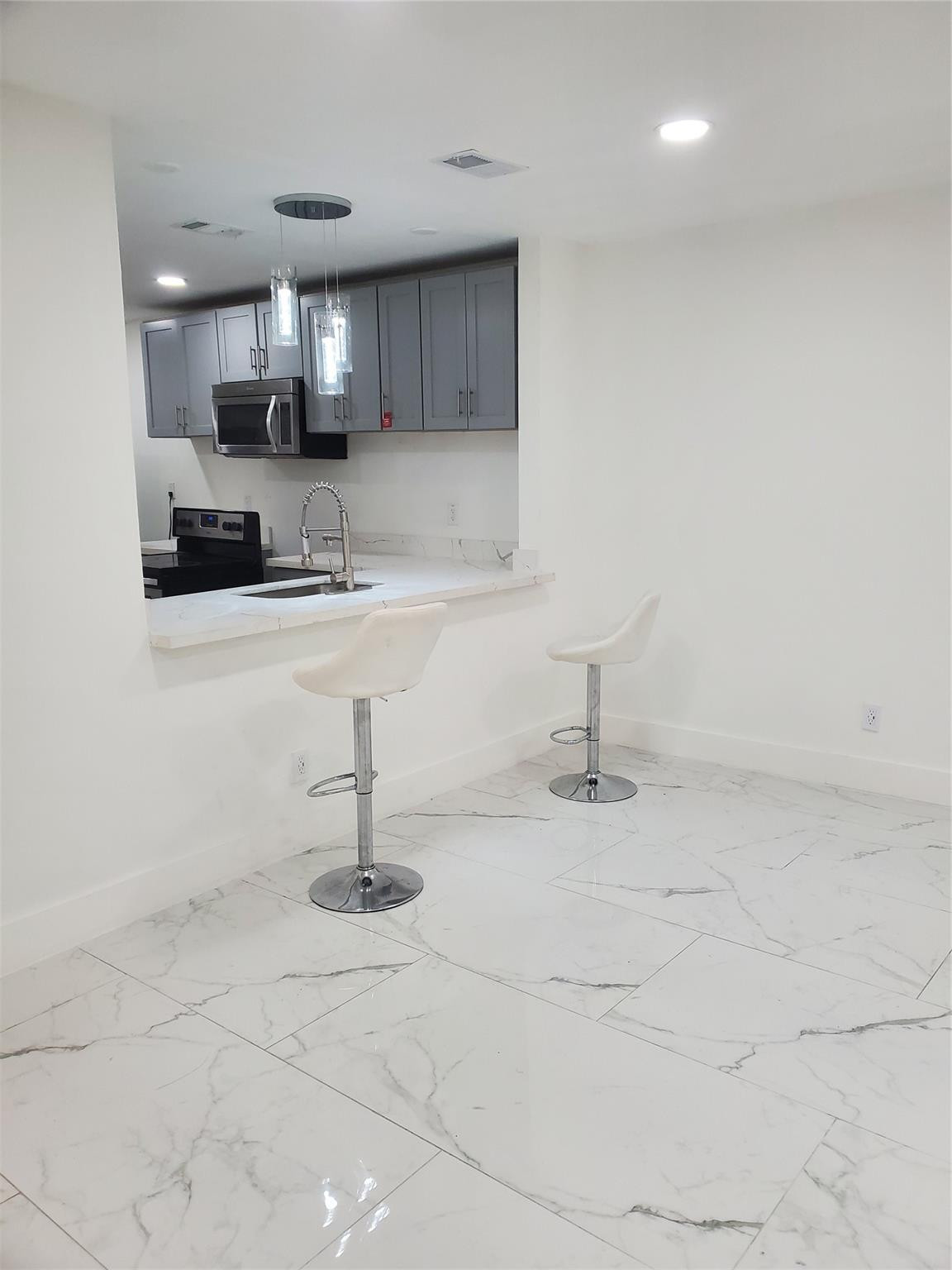 Undisclosed Address Tamarac, FL 33319 - Photo 8 of 21 a kitchen with stainless steel appliances a sink a stove a microwave and cabinets