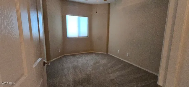 an empty room with a chandelier fan and windows