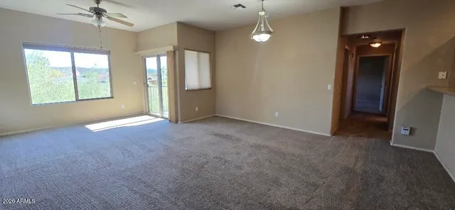 en empty room with windows and chandelier fan