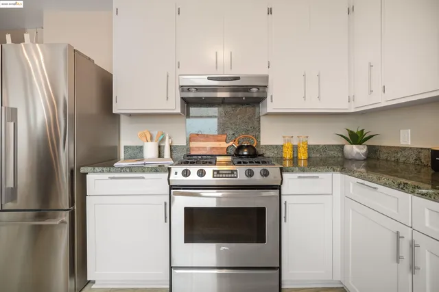 a kitchen with stainless steel appliances granite countertop a stove a refrigerator and a white cabinets