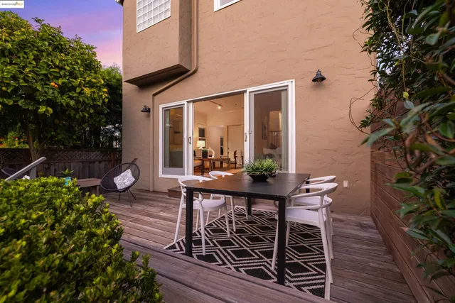 a view of a patio with table and chairs potted plants and floor to ceiling window and wooden fence