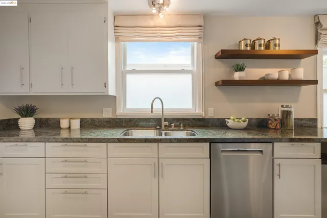 a kitchen with granite countertop white cabinets and a window