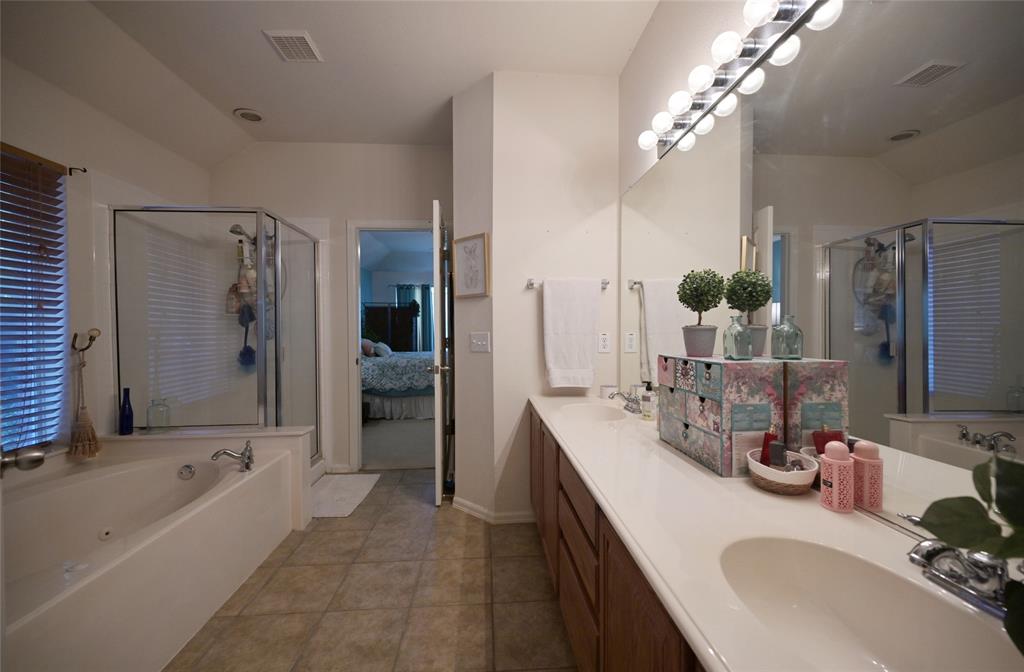 4509 Butterfly Way Fort Worth, TX 76244 - Photo 23 of 40 a bathroom with double vanity sinks a large mirror and a bathtub