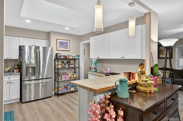 a kitchen with a refrigerator a stove a sink dishwasher and a dining table with wooden floor