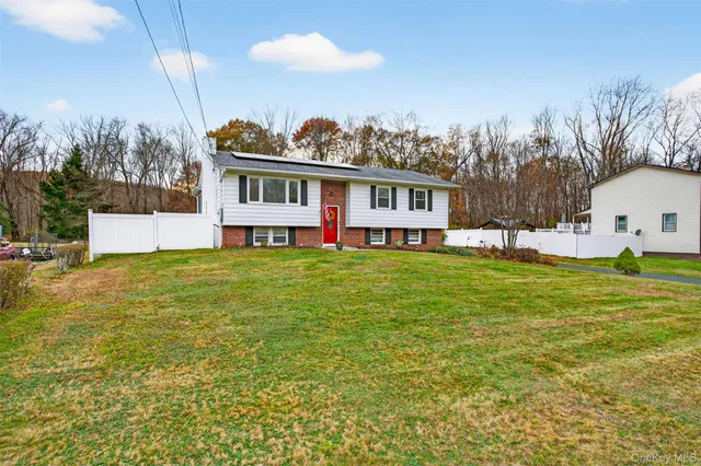a front view of house with yard and trees in the background