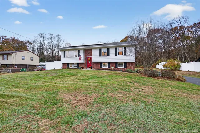a house that is sitting in the grass with large trees and plants