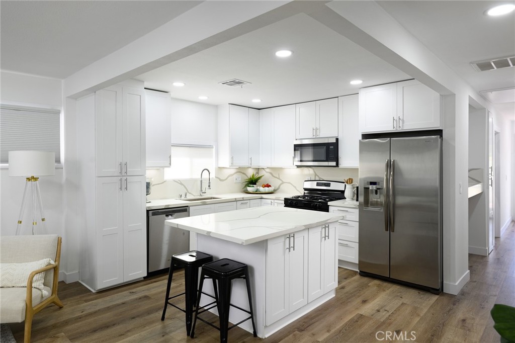 4705 East Washington Avenue Orange, CA 92869 - Photo 6 of 41 a kitchen with a refrigerator a sink dishwasher and a stove with wooden floor