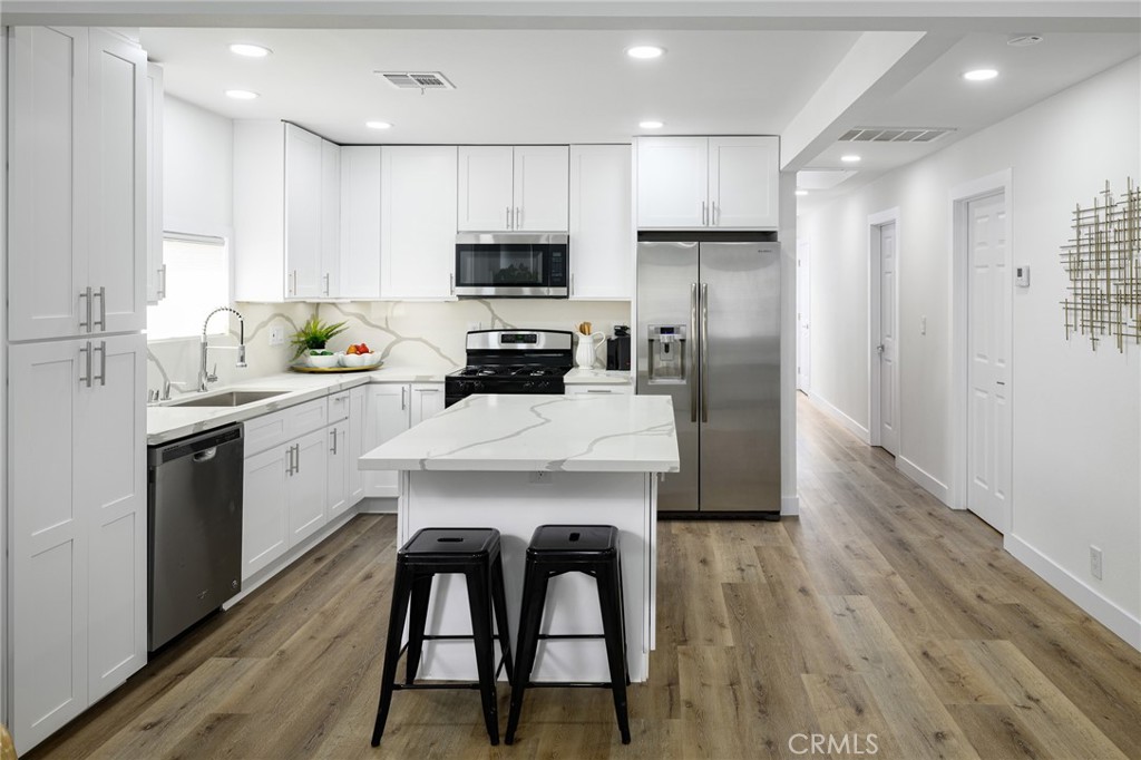 4705 East Washington Avenue Orange, CA 92869 - Photo 9 of 41 a kitchen with a sink a microwave a refrigerator and cabinets