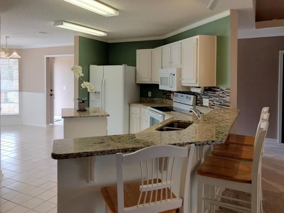 5196 Whitehurst Lane Crestview, FL 32536 - Photo 7 of 13 a kitchen with a table chairs a refrigerator and a stove
