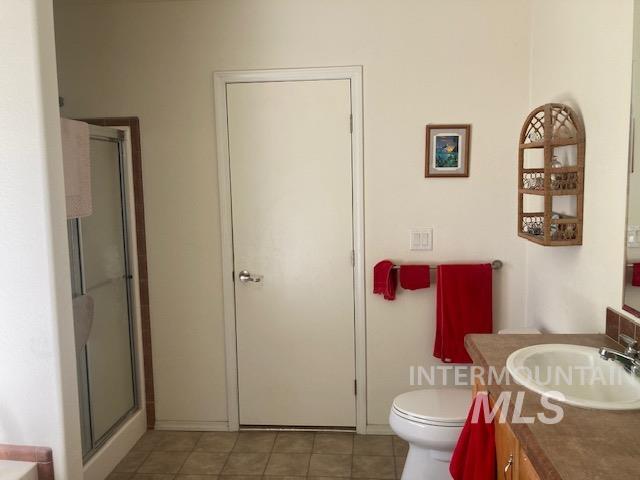 1095 County Road 70 Weiser, ID 83672 - Photo 18 of 44 Bathroom featuring a white toilet, a shower with a sliding glass door and tile surround, and a vanity with a white sink and laminate countertop