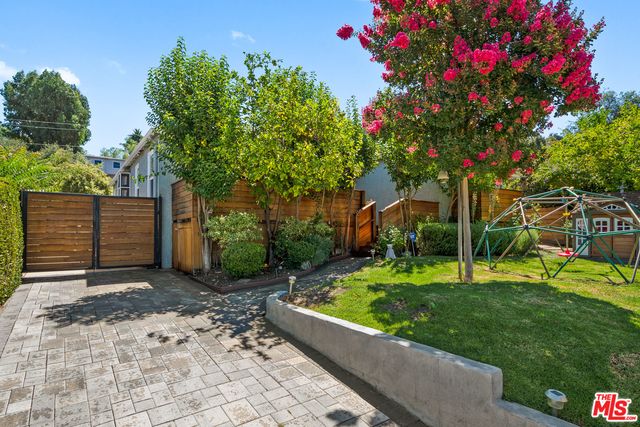 a pathway of a house with a big yard and potted plants