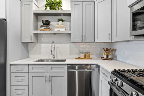 a kitchen with white cabinets and stainless steel appliances