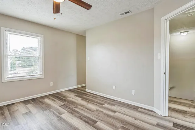 a view of empty room with window and ceiling fan
