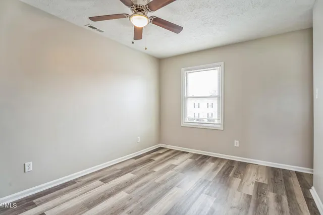 an empty room with a window and ceiling fan