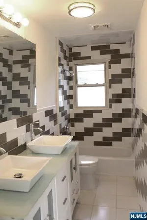 a bathroom with a double vanity sink toilet and mirror