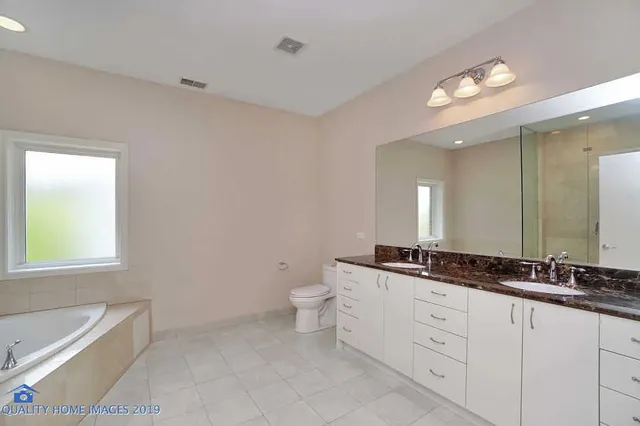 a spacious bathroom with a granite countertop double vanity sink a mirror and a bathtub