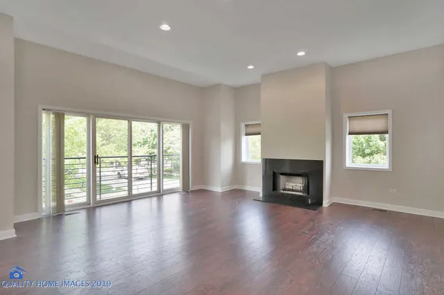 an empty room with windows a fireplace and wooden floor