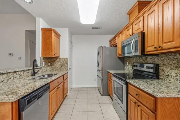 a kitchen with stainless steel appliances granite countertop a sink and a refrigerator
