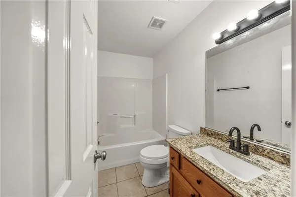 a bathroom with a granite countertop sink a toilet and shower