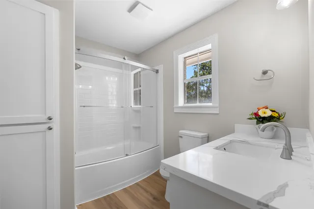 an empty room with wooden floor chandelier fan and windows