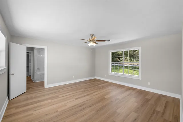a view of an empty room with wooden floor and a window