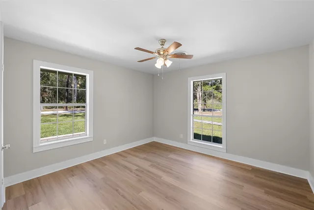 a view of empty room with wooden floor and fan