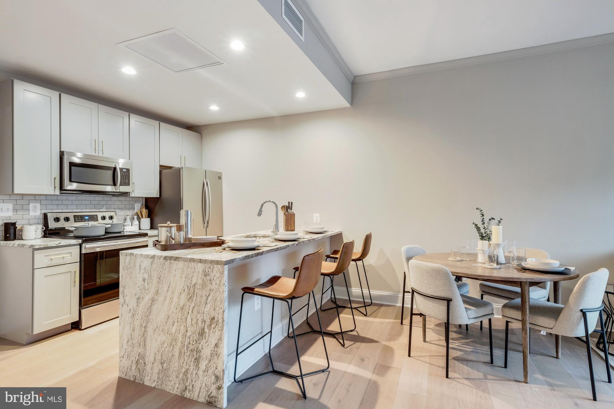 30 North 23rd Street, Unit 1906 Philadelphia, PA 19103 - Photo 6 of 42 a kitchen with kitchen island a stove a table and chairs in it