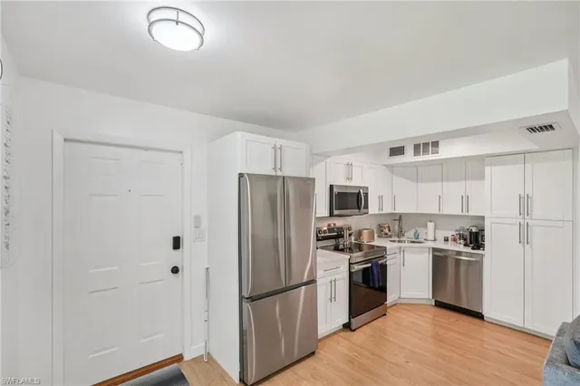 a kitchen with a refrigerator a stove top oven and wooden floor