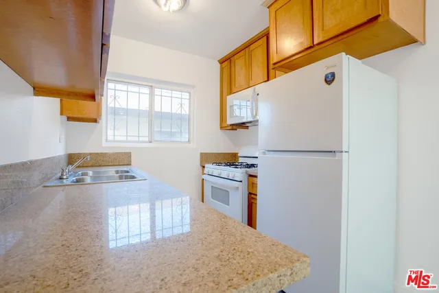 a kitchen with a refrigerator a stove top oven a sink and a window