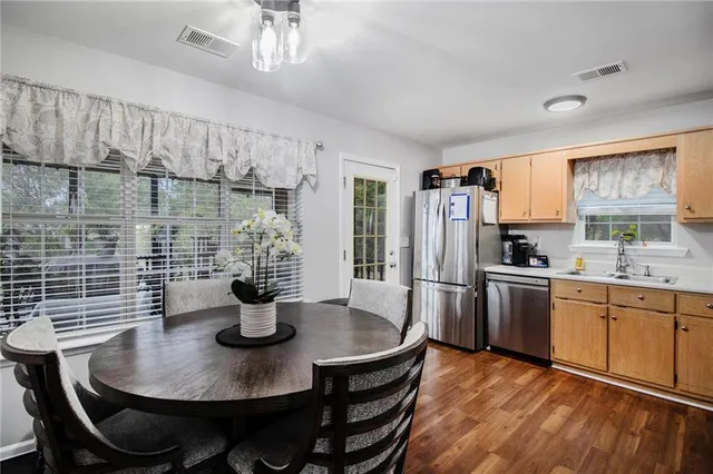 a kitchen with stainless steel appliances a dining table chairs and a refrigerator