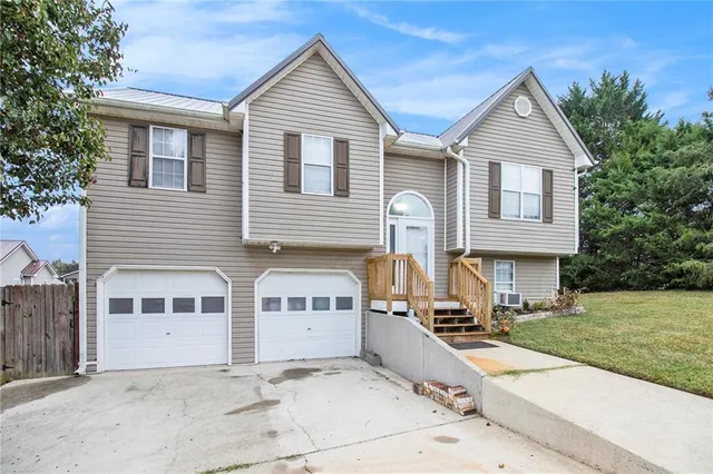 a view of a white house with a small yard and large trees