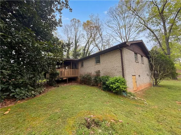 a view of a house with a large tree and a yard