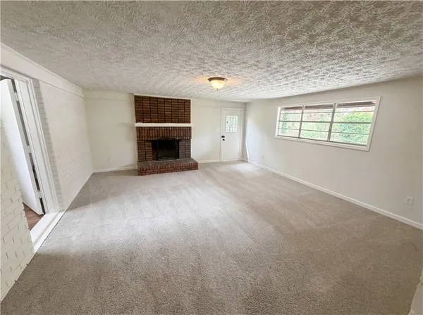 an empty room with windows and fireplace
