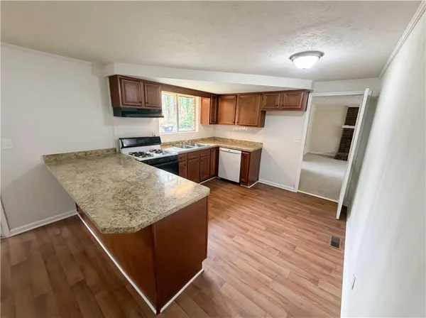 a kitchen with stainless steel appliances granite countertop a sink dishwasher stove and microwave with wooden floor