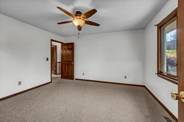 an empty room with windows and chandelier fan