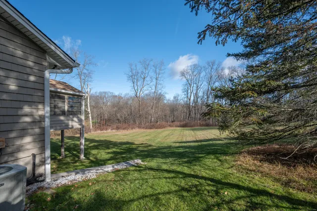 a view of a house with a big yard and large trees