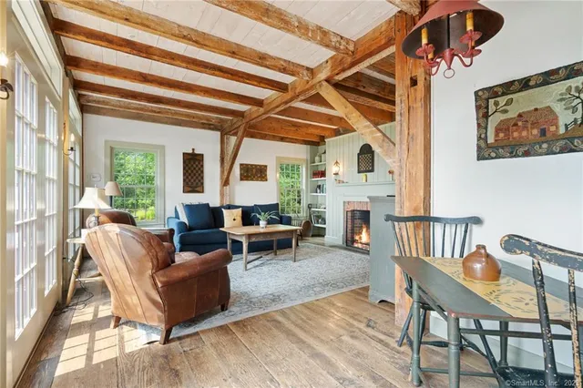 a living room with furniture a fireplace and a dining table with wooden floor