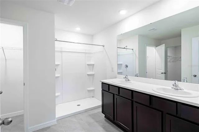 a bathroom with a shower sink double vanity and mirror